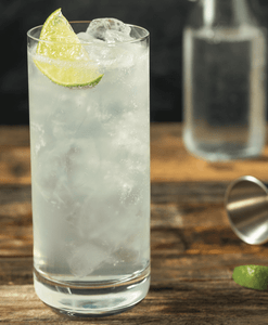 Tall glass of tequila on ice with lime wedge
