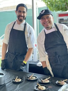 The Select workers offering bites of lamb on a white clothed table at Food That Rocks 2021