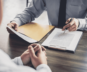 man going over legal issues with a client sitting across the wooden table from him.