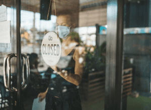 Woman flipping over a closed sign on her restaurant window