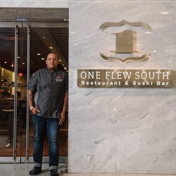 Chef Todd Richards standing beside the One Flew South sign. Photo courtesy of One Flew South.