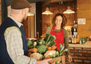 man delivering fresh produce to woman in an apron