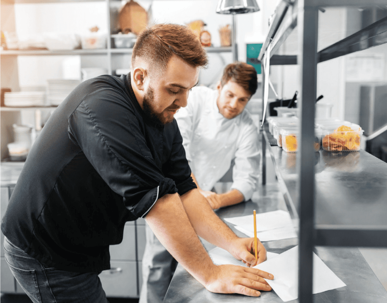 man signing papers in the kitchen at his restaurant