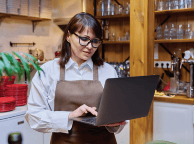 Woman holding computer while working in her restaurant.