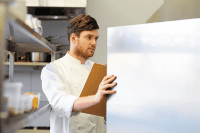 Man staring into fridge at a restaurant.